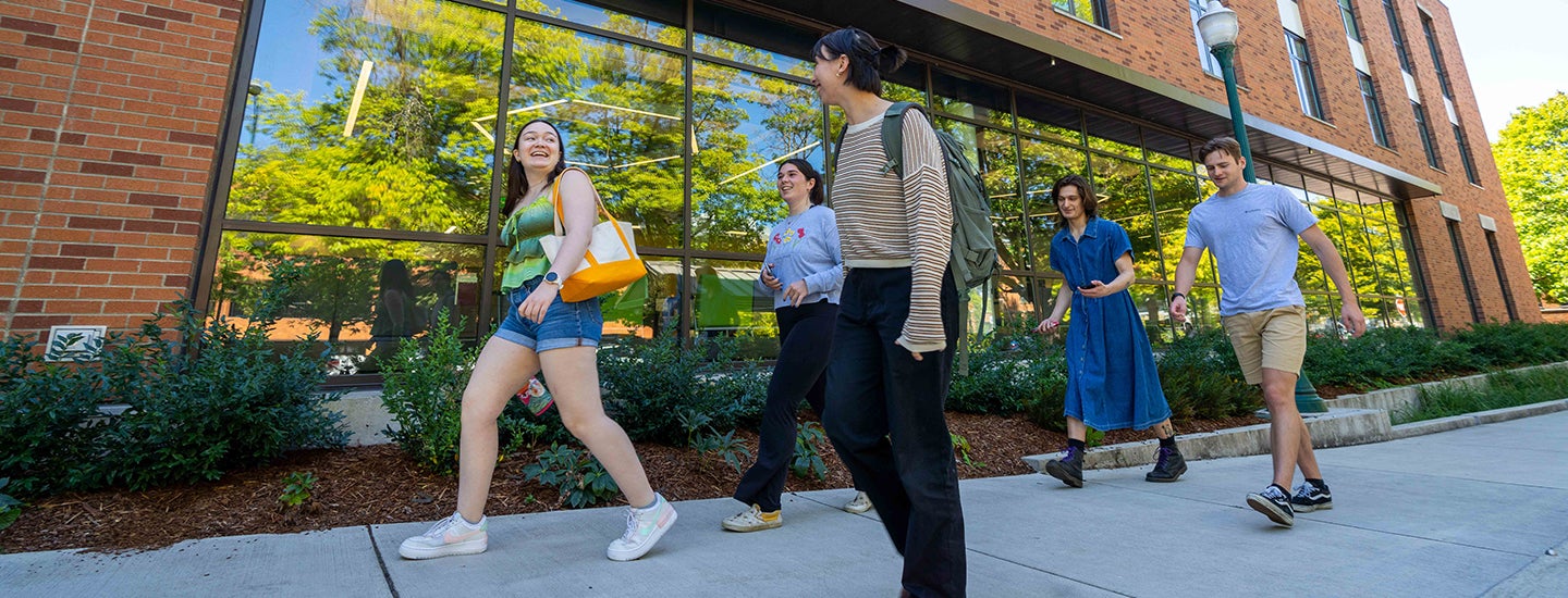 Four students walk toward the entrance of the health services building