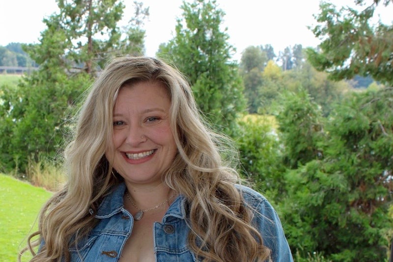 Brandy Kivett in a denim jacket with trees in the background